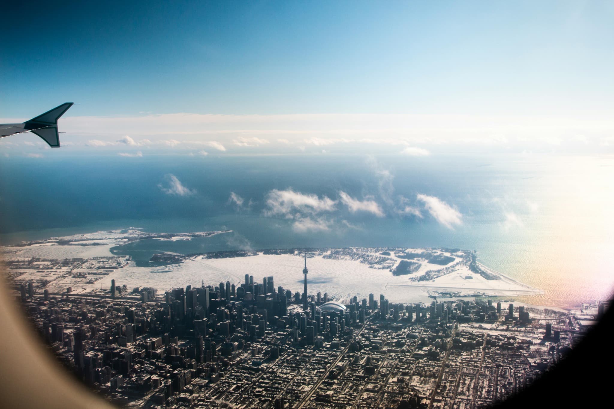 Aerial view of snow-covered Toronto and the CN Tower from an airplane window.
